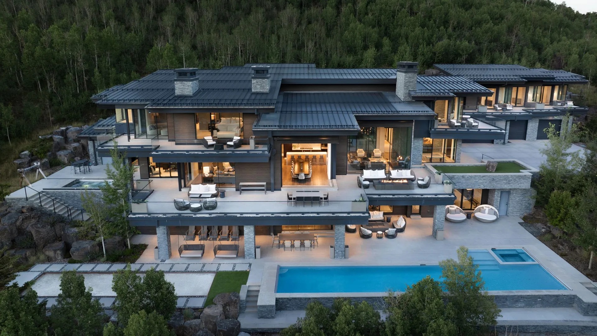 Aerial view of the full residence and pool terrace set into the wooded hillside