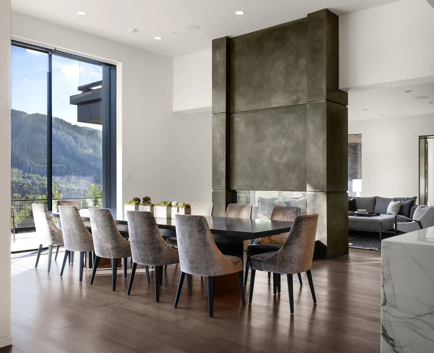 Dining room with sculptural ring pendant and glass walls opening to the landscape