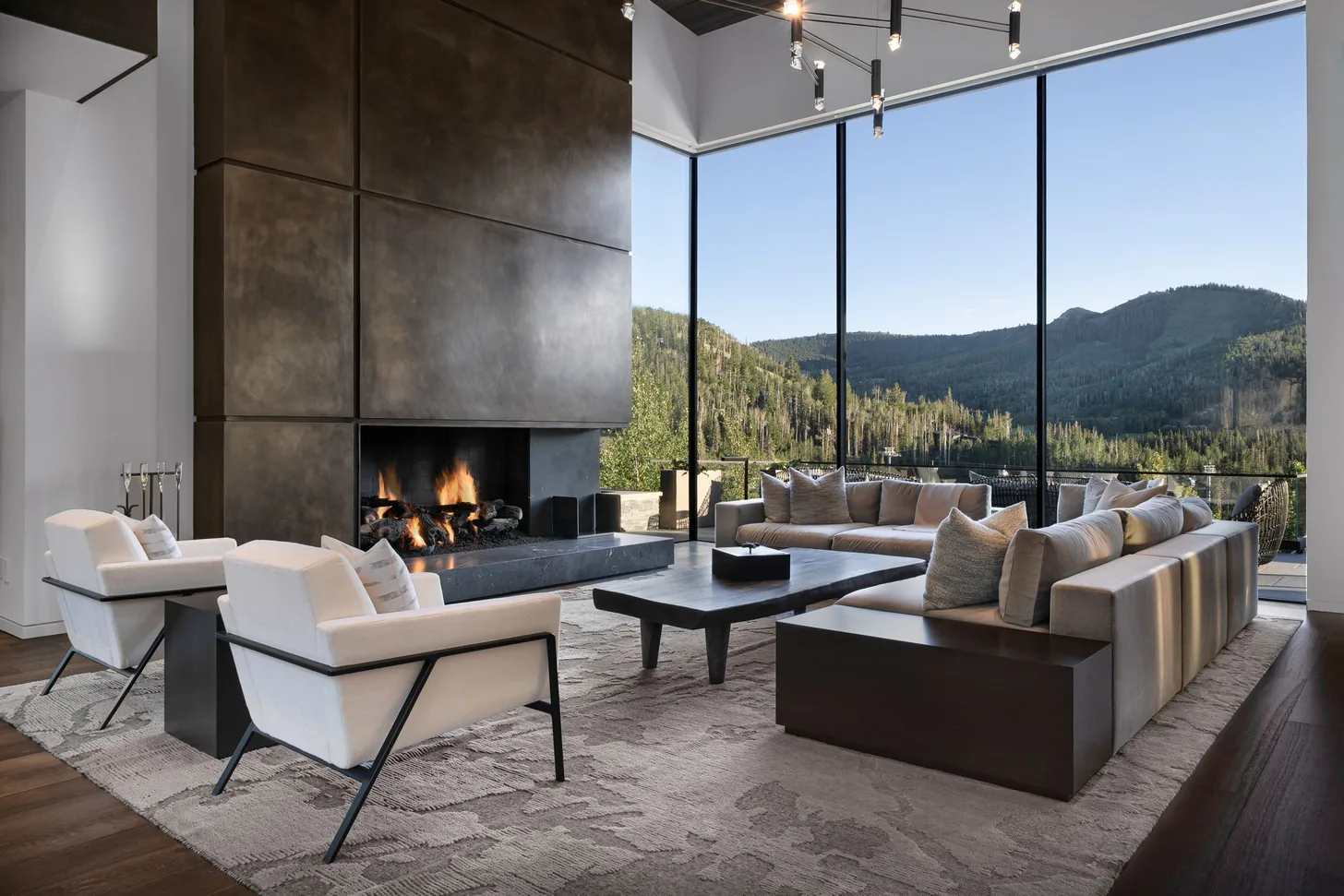 Living room fireplace alight with mountain views through floor-to-ceiling glass