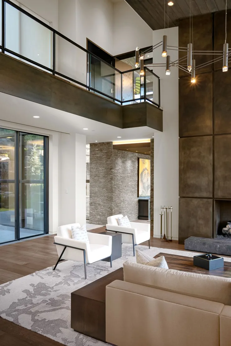 Double-height great room with upper glass gallery and layered stone and timber finishes
