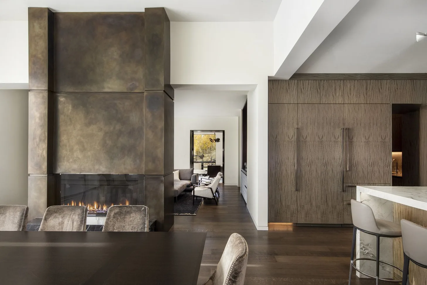Patinated bronze fireplace surround between the dining table and the kitchen