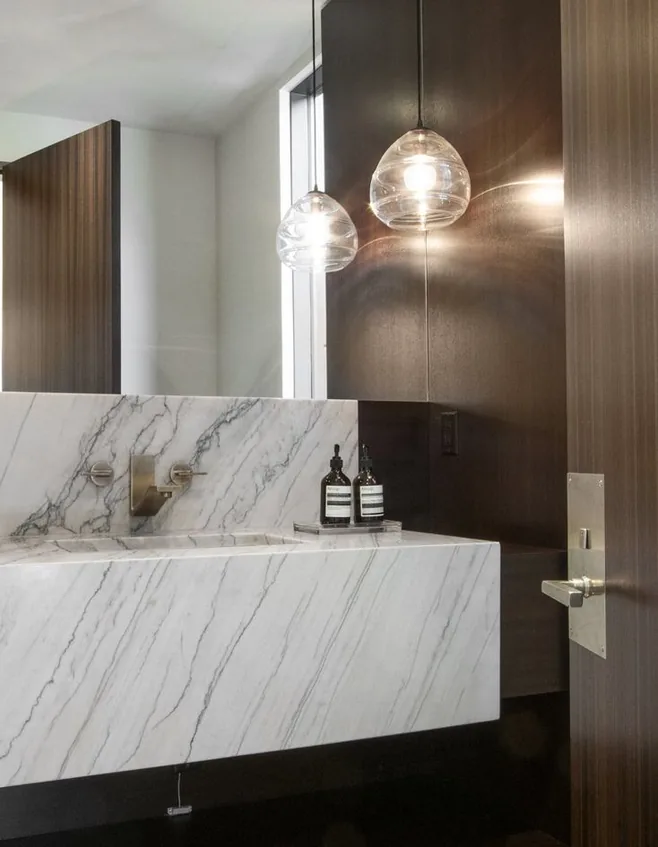 Powder room with book-matched marble vanity and glass globe pendants