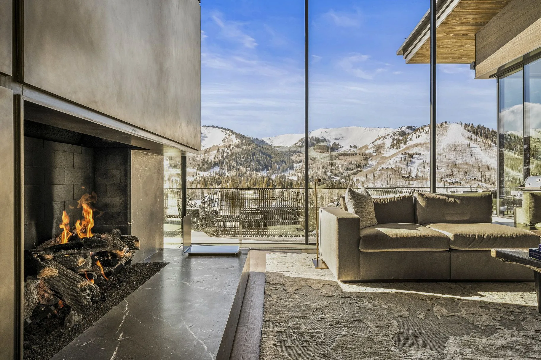 Stone fireplace burning against a snow-covered mountain view in winter