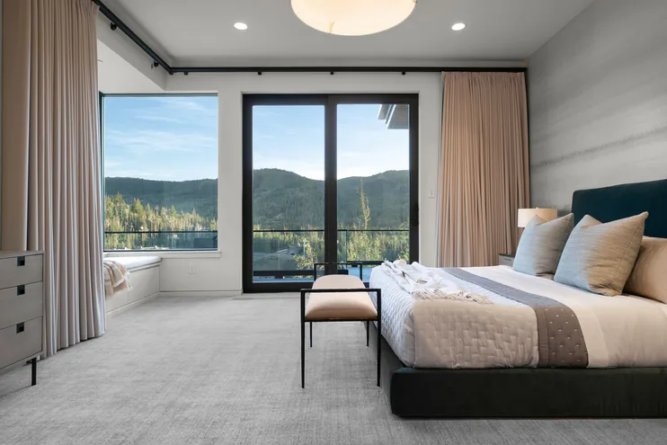 Guest suite with soft textiles and a seating area beside the window wall
