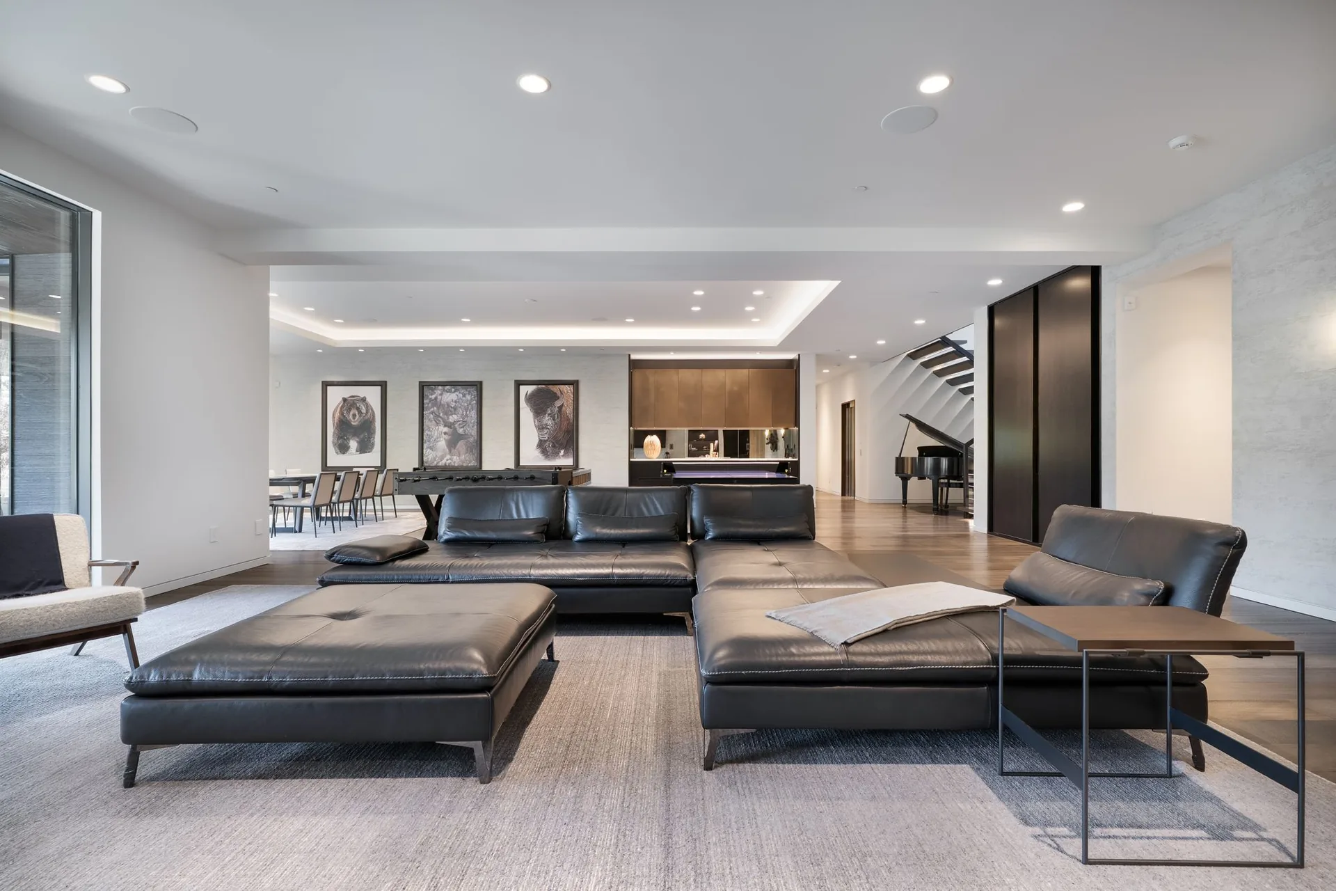 Lower living lounge with leather seating opening to the game room and piano beyond