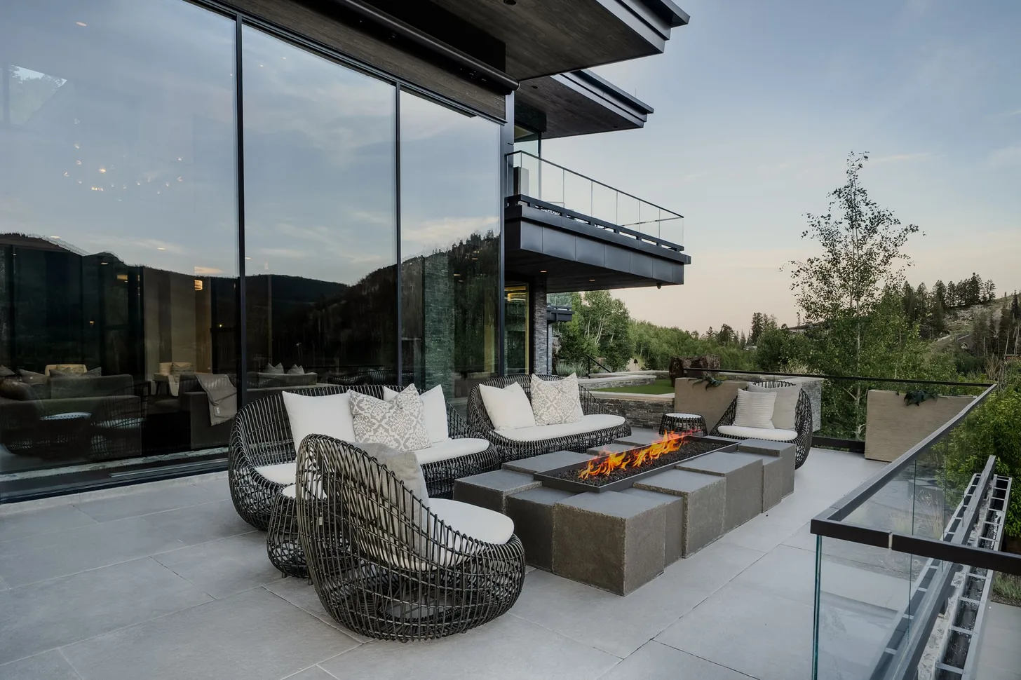 Outdoor living terrace with fire table and lounge seating at dusk