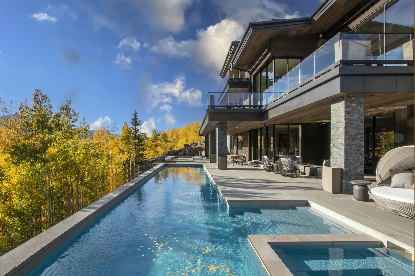 Infinity pool and spa running alongside the terrace with golden aspens beyond