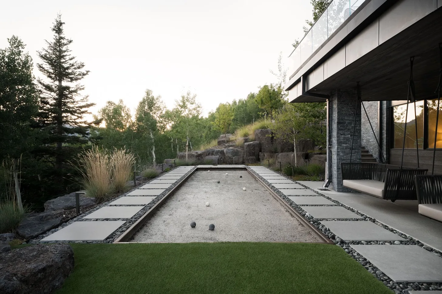 Custom bocce court in cut stone beside the lawn and terrace
