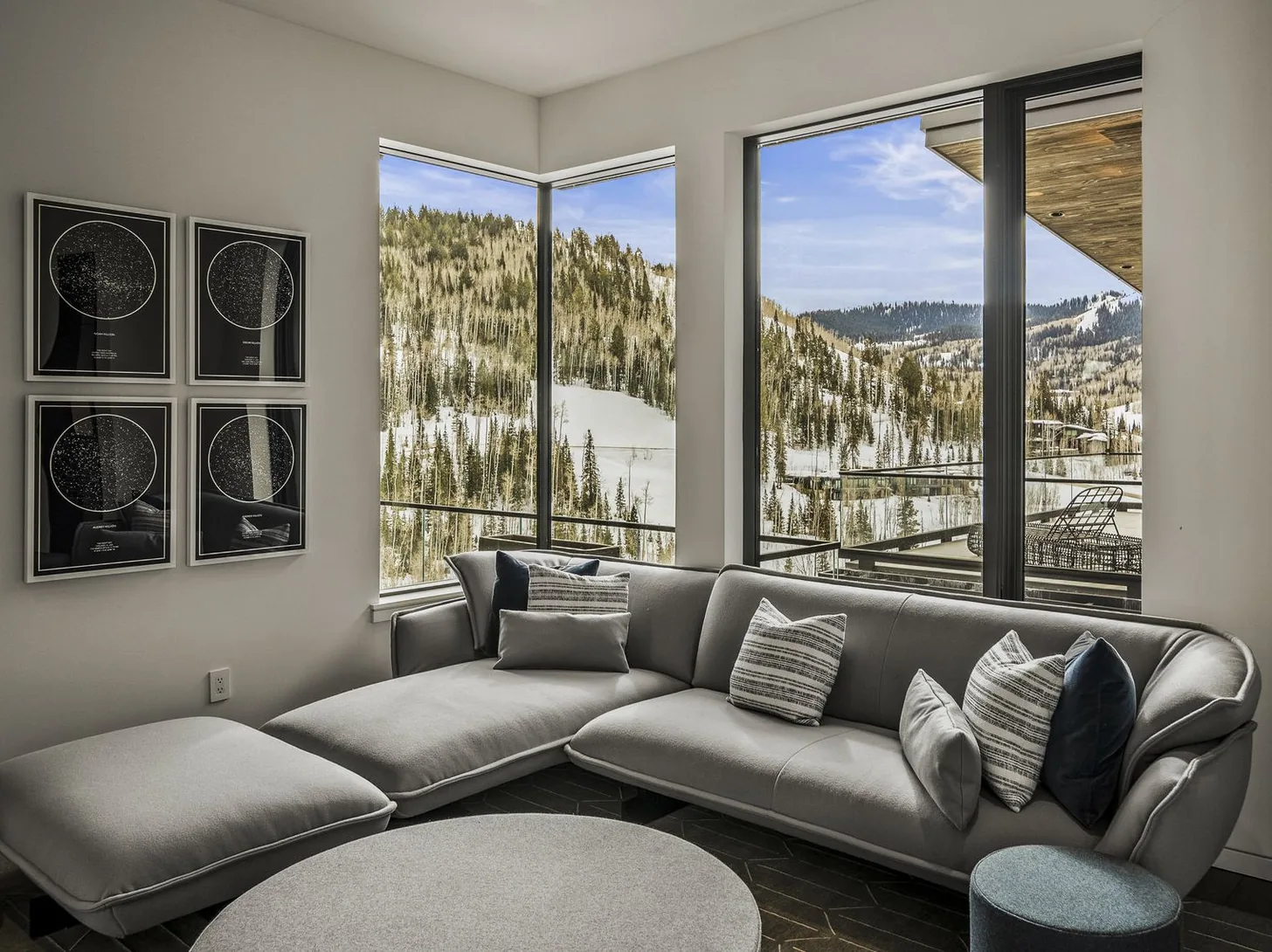 Guest lounge with a curved sectional and corner windows onto snow-covered aspens