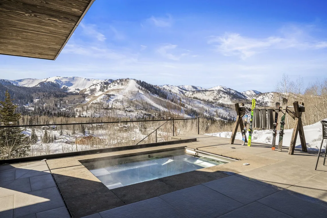 Skis planted beside the spa terrace with snow-covered ski runs beyond